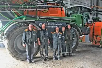 Работники перед сельскохозяйственной машиной