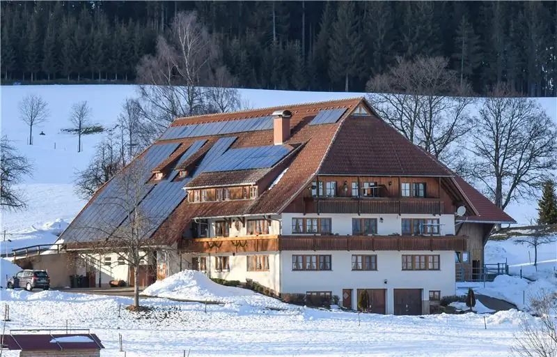 Заснеженный фермерский дом в Шварцвальде с солнечной системой на крыше