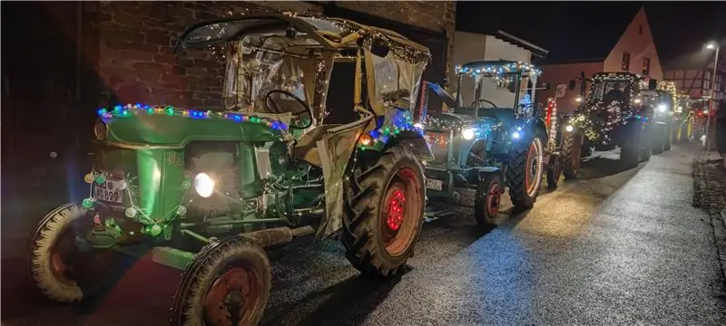 Несколько старинных тракторов подряд с множеством гирлянд