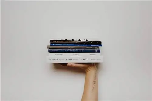 Женщина с татуировкой держит стопку книг. Женщина с татуировкой держит стопку книг.