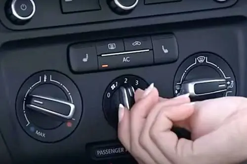Женщина крутит ручку кондиционера в машине