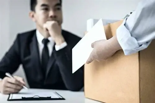 Скептически настроенный азиатский мужчина перед другим держит картонную коробку