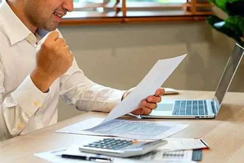 Мужчина в белой рубашке с веселым выражением лица держит простыню