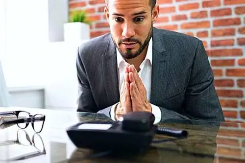 Мужчина в костюме, который, кажется, попрошайничает перед столом