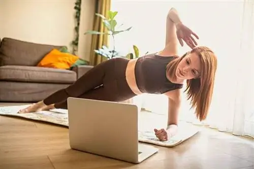 Женщина делает боковую обшивку перед своим компьютером в своей гостиной.