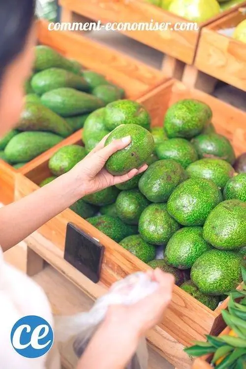 Руки собирают спелый авокадо из деревянного ящика, полного авокадо.