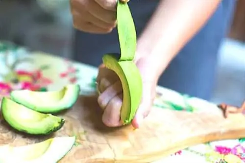 Рука стягивает кожуру с авокадо, как с банана