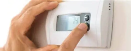 Руки регулируют термостат на белом фоне.