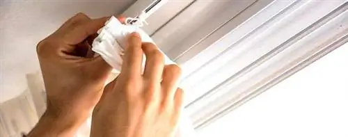 Руки, которые вешают белую занавеску.