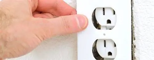 Рука, снимающая крышку электрической розетки.