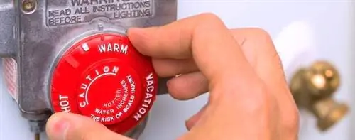 Рука регулирует красную ручку котла.