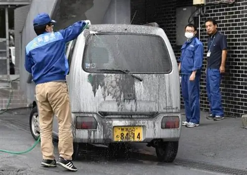 Сотрудник городского правительства чистит машину, покрытую вулканическим пеплом, образовавшимся из кратера извержения вулкана Асо в Асо, префектура Кумамото, юго-западная Япония, на этой фотографии, сделанной Киодо 8 октября 2016 года. Обязательное указание Киодо/через REUTERS