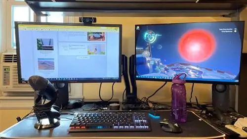 Два игровых монитора, микрофон, игровая клавиатура и коврик для мыши XXL перед стеной.