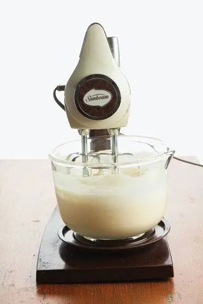Настольный миксер Sunbeam работает со стеклянной миской с тестом для торта. Настольный миксер Sunbeam работает со стеклянной миской с тестом для торта.