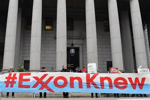 Люди стоят перед зданием суда с большим транспарантом с надписью ExxonKnew