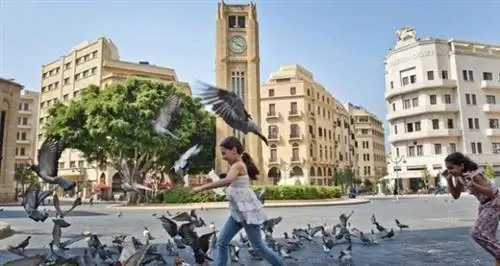 Девушка гоняется за голубями на площади в Бейруте.