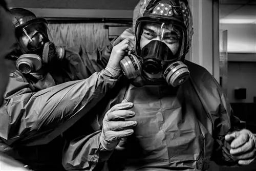 Врач Джеральд Форе (справа) надевает защитную маску перед приемом пациентов с COVID-19 в больнице Богоматери.