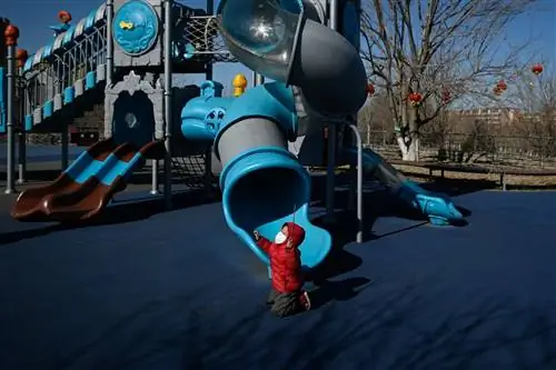 Мальчик в маске играет на детской площадке на одной из улиц Пекина, Китай.