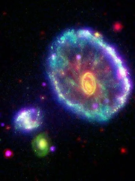 Этот снимок галактики Колесо Телеги в искусственных цветах был создан путем объединения изображений, сделанных четырьмя космическими аппаратами.
